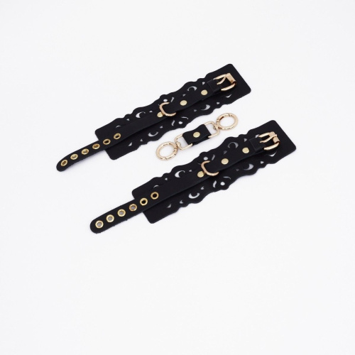 Черные кожаные наручники с узорами и золотистой фурнитурой